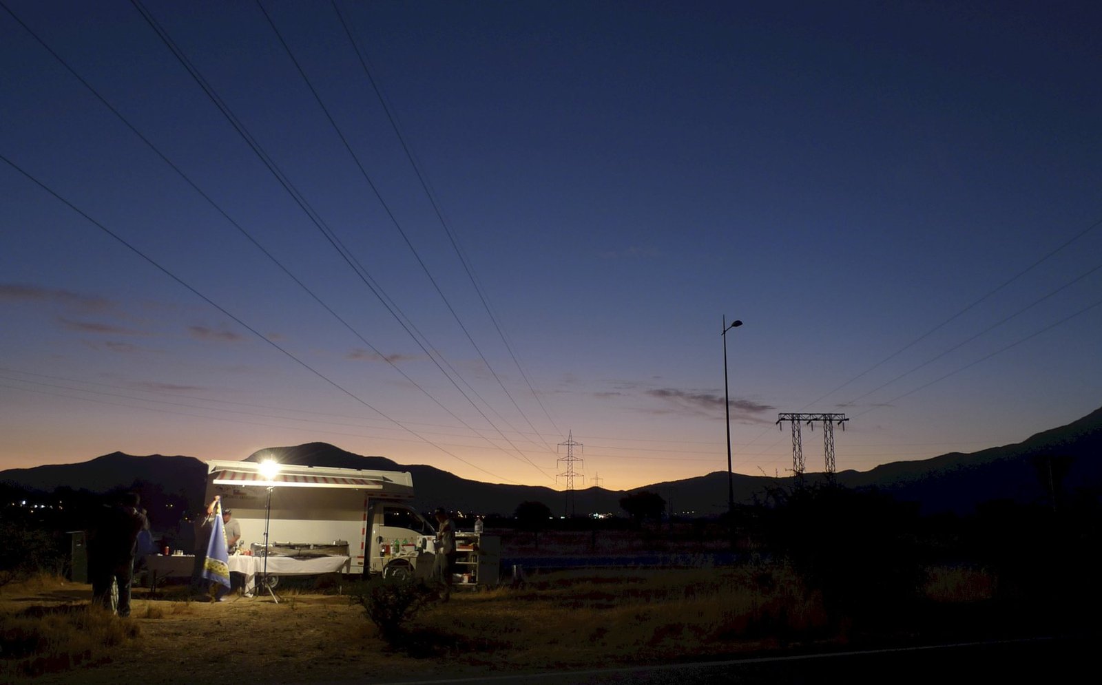 Unidad iluminada operando al anochecer, con la cordillera al fondo